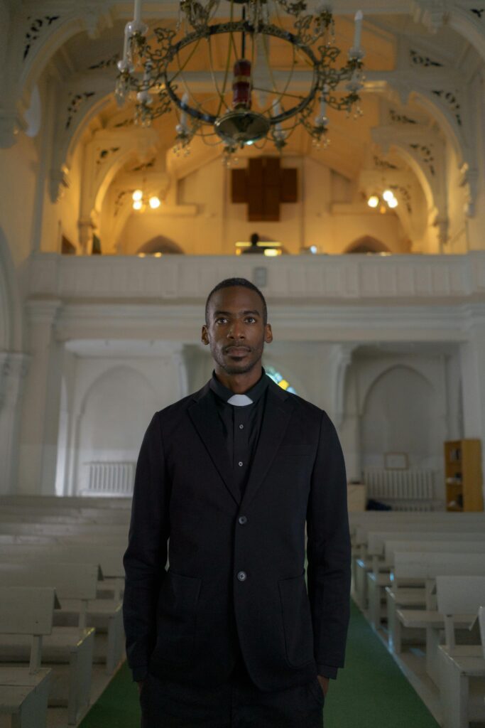 pexels-photo-6284491-6284491 A pastor stands confidently in a beautifully ornate Gothic church interior, exuding faith.