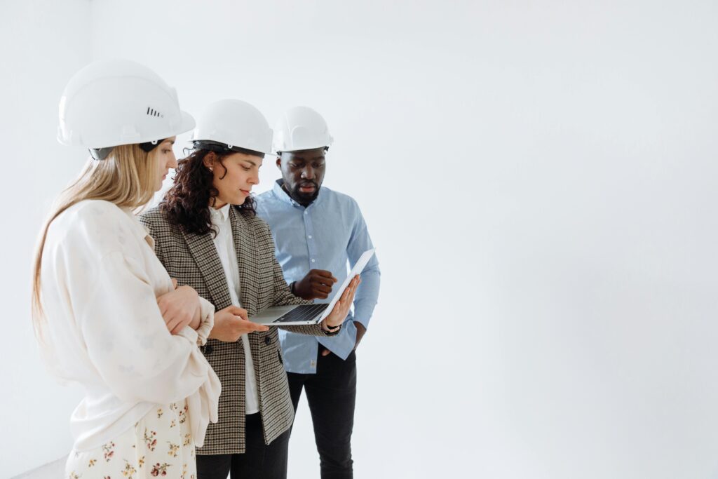 pexels-photo-8470778-8470778 Engineers in hard hats reviewing plans on a laptop indoors.